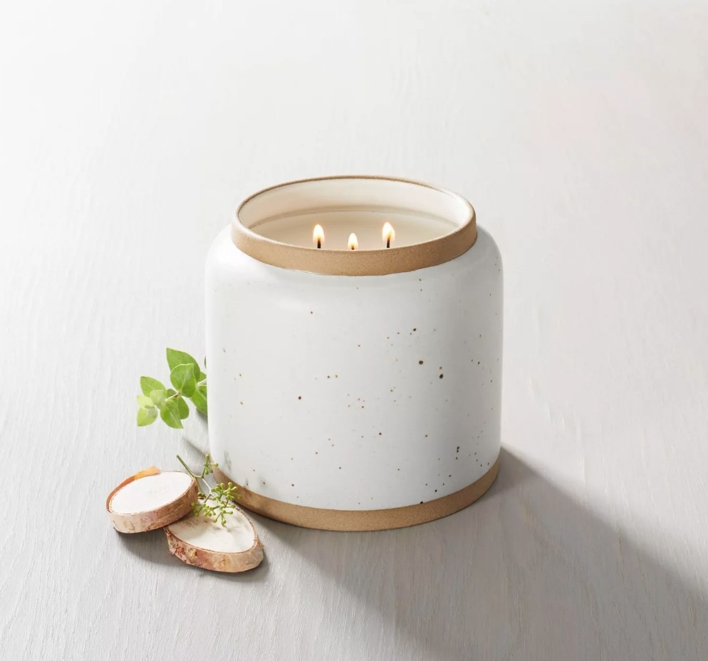 A cream/speckled, ceramic candle with 3 wicks