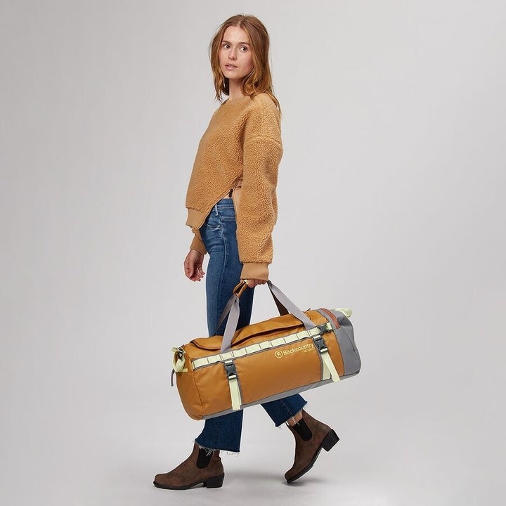 a model carrying a yellow duffle bag