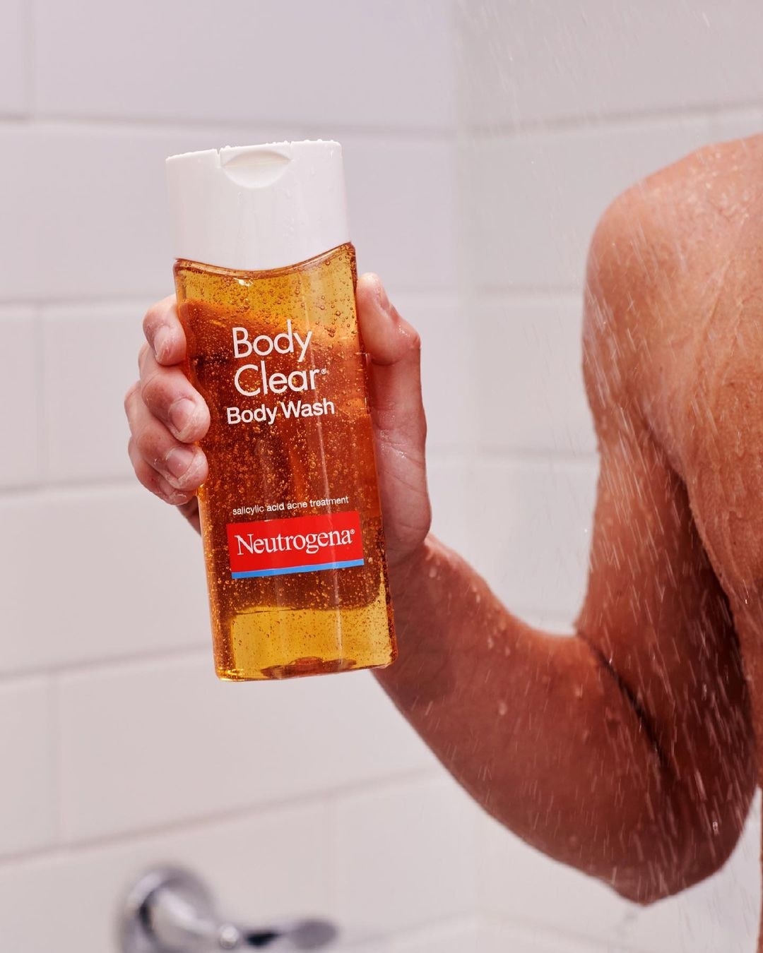 A person holding up a bottle of the acne-clearing wash in the shower