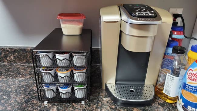 reviewer image of the K-cup organizer next to a keurig machine on a kitchen counter