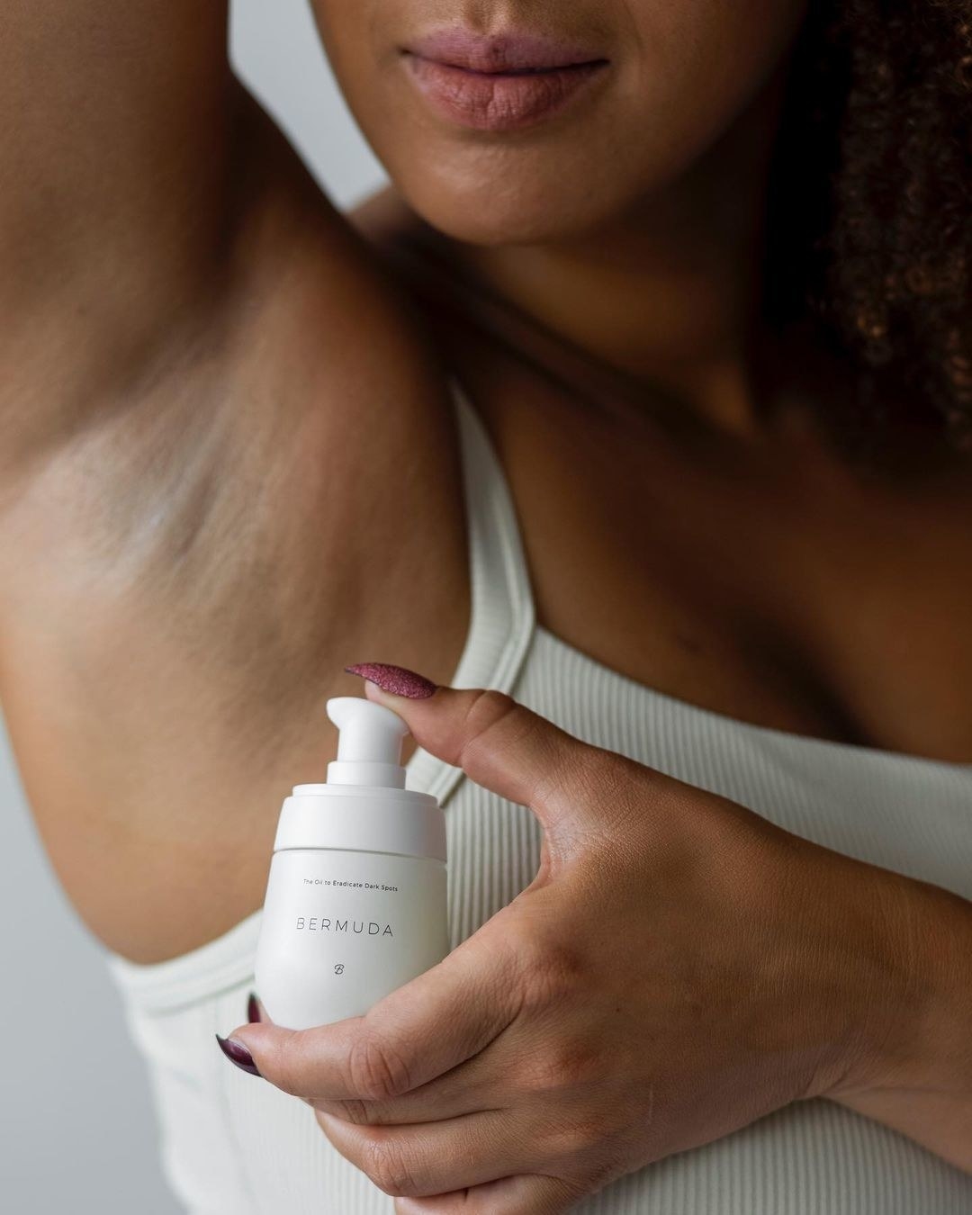 A person holding up a bottle of the treatment oil under their armpit