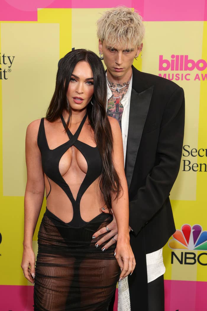 MGK holding onto Megan&#x27;s waist as they pose for photos on a red carpet