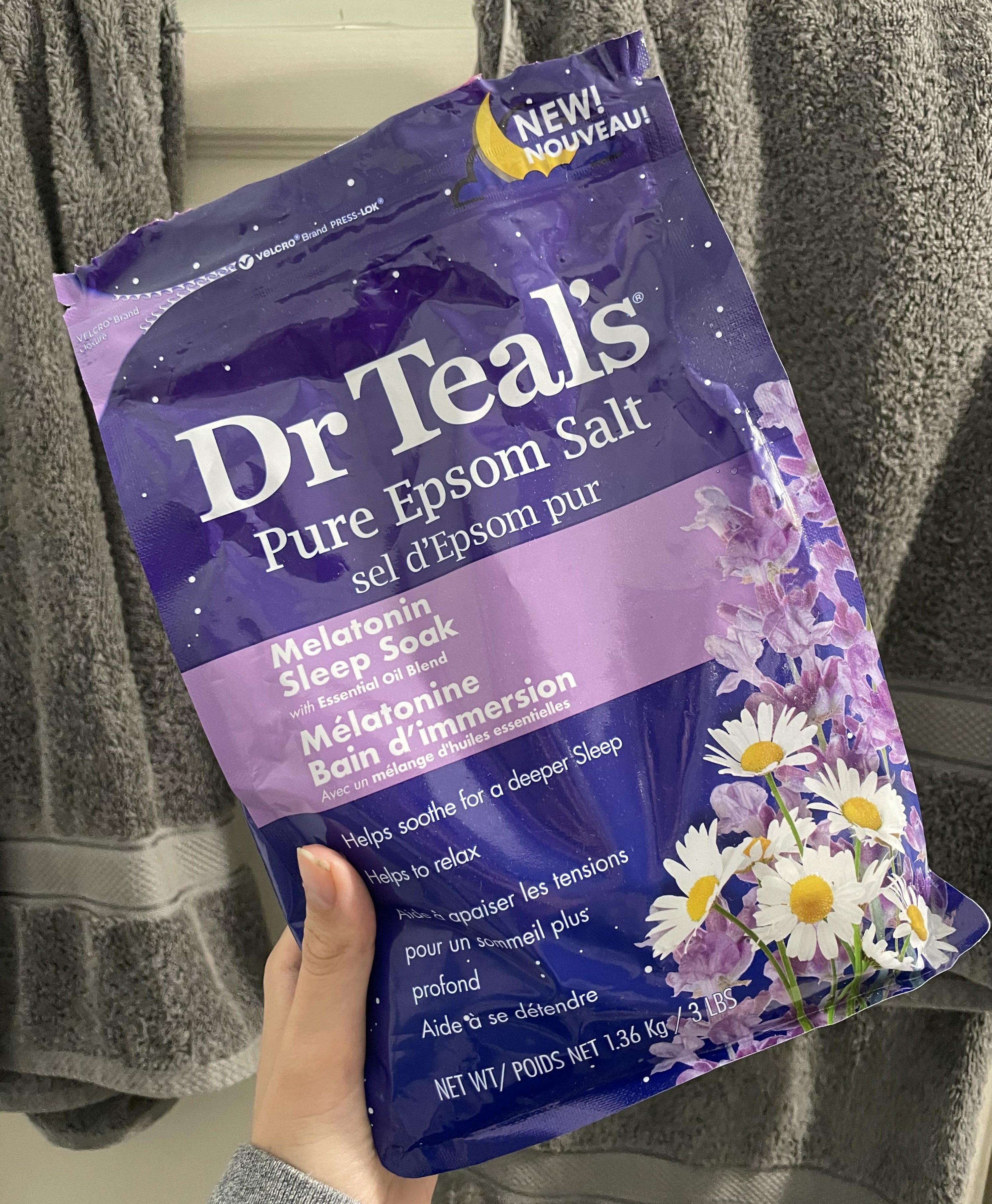 A person holding the bag of Epsom salts in front of towels