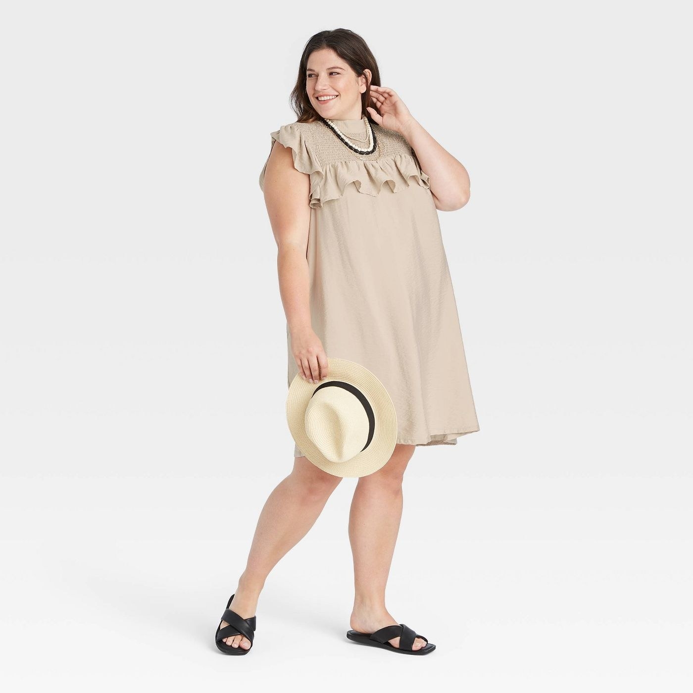 AA model wearing a sleeveless tan ruffle dress