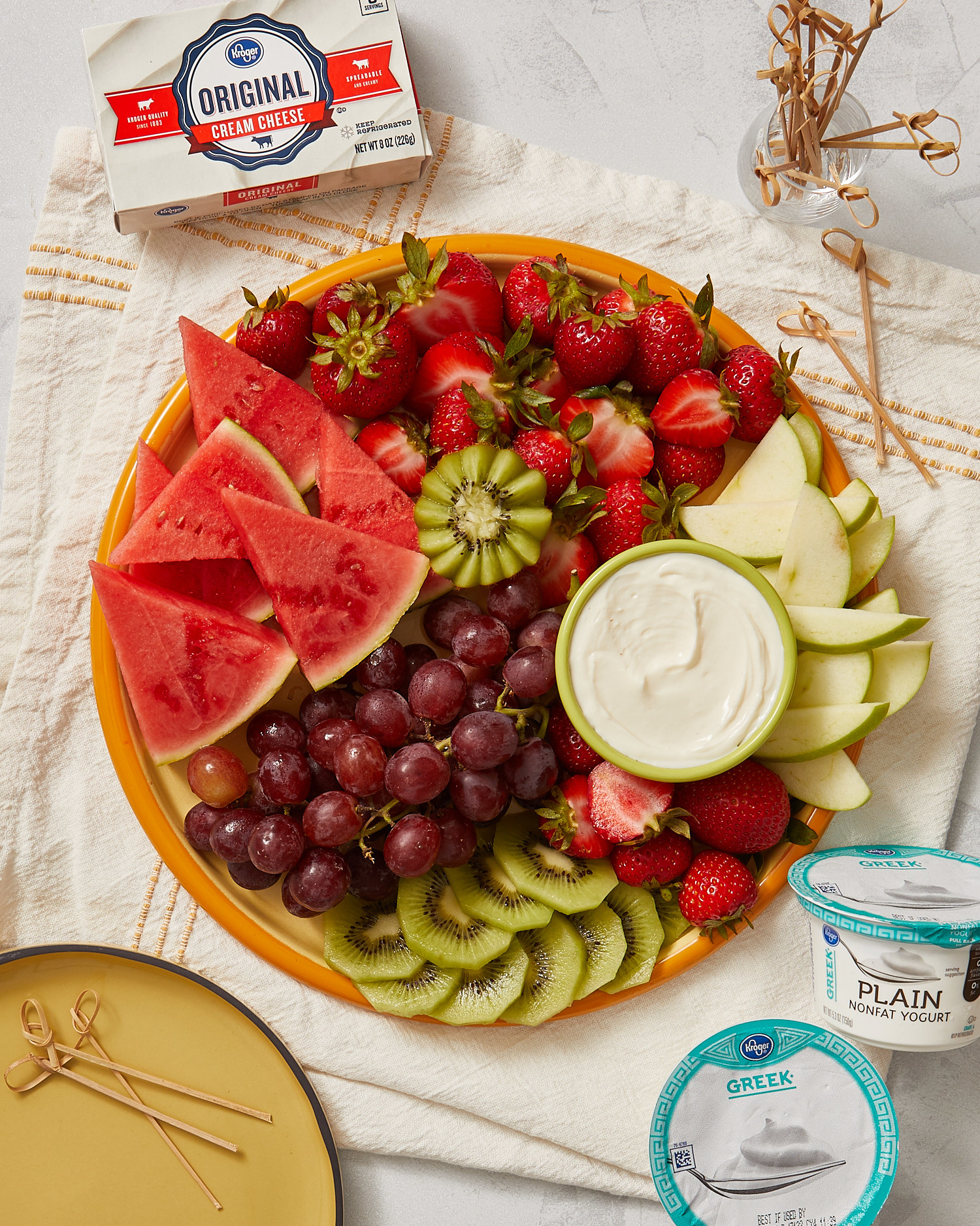 Platter with grapes and kiwi and strawberries and watermelon served with small bowl of sweet cream cheese dip