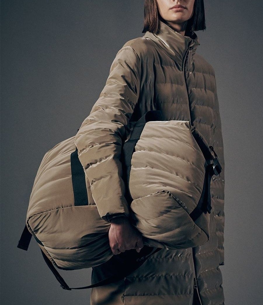 A person holding the oversized waterproof bag while wearing the matching coat