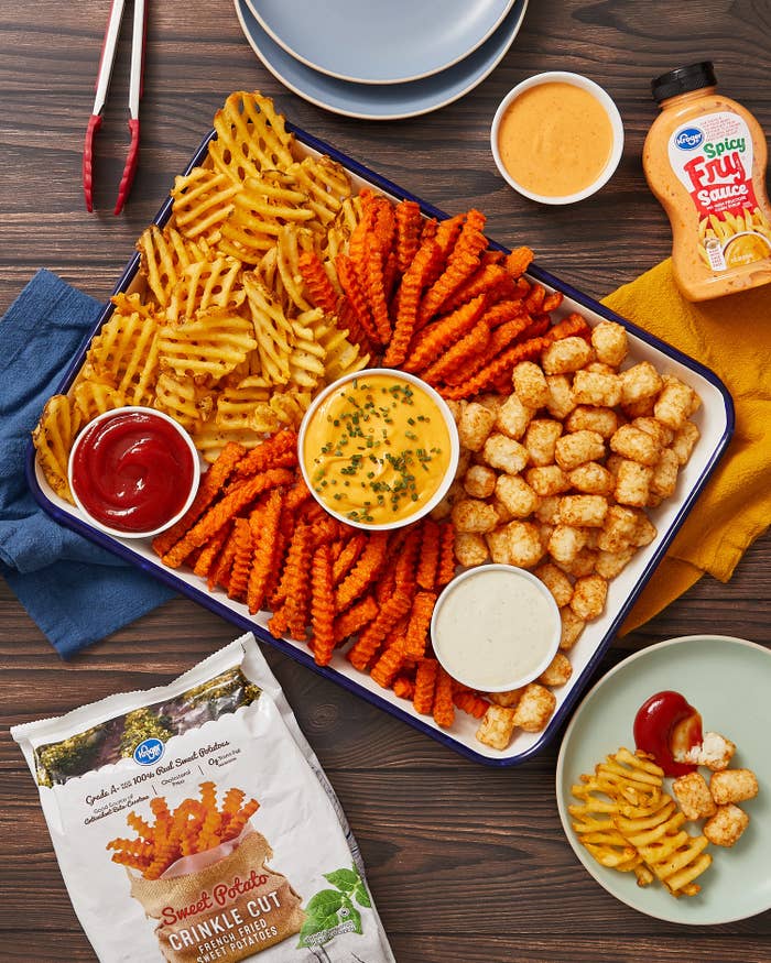 Sweet potato fries and waffle fries and tater bits on a platter surrounding small sauce bowls