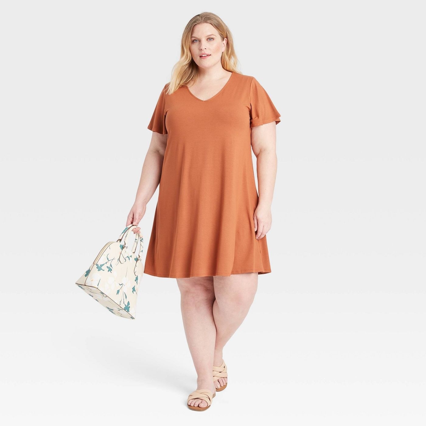 A model wearing an orange knit dress with a flutter sleeve