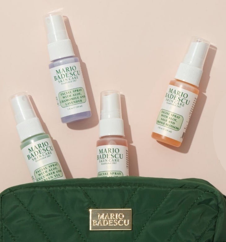 A set of four mini mario badescu face sprays spilling out of a makeup bag