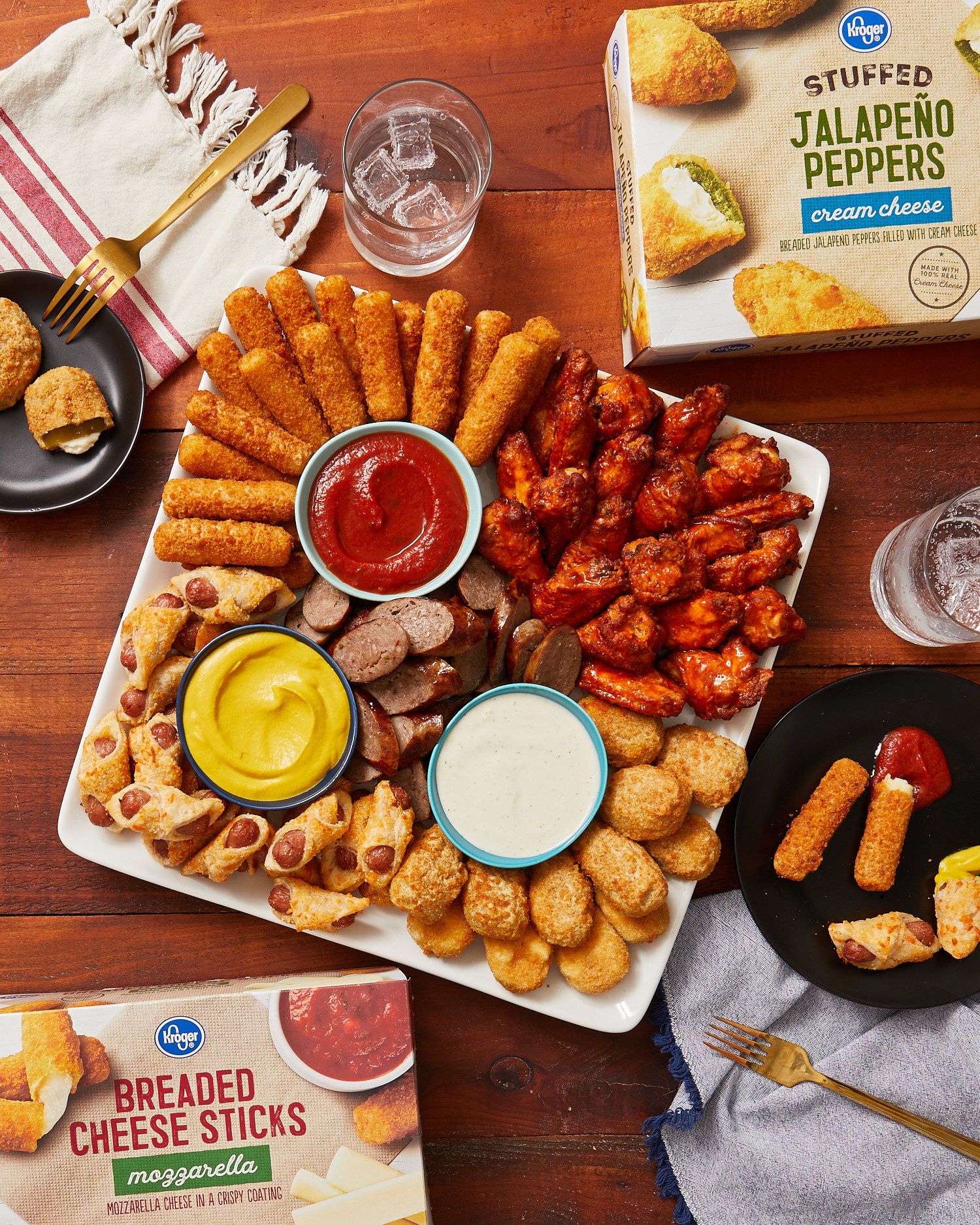 Plate filled with appetizers and small sauce bowls containing ranch and mustard and marinara sauce