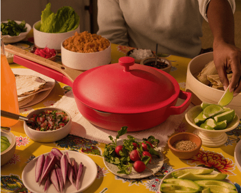 red Our Place pan on tabletop around chef and veggie plates