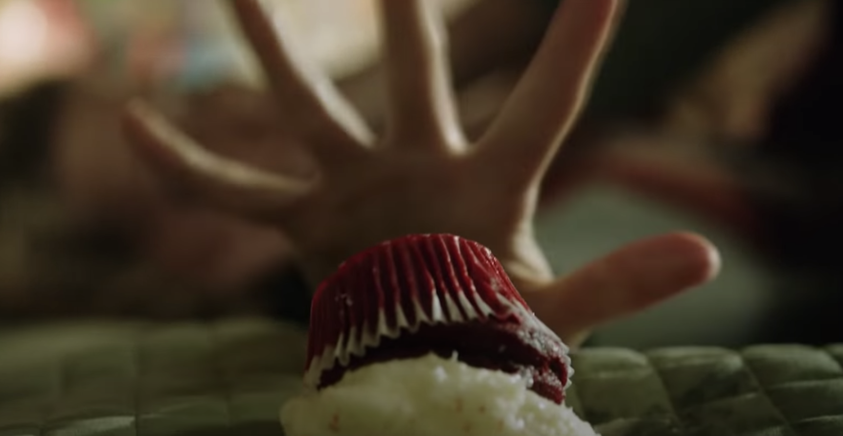 A hand desperately grabs for a cupcake