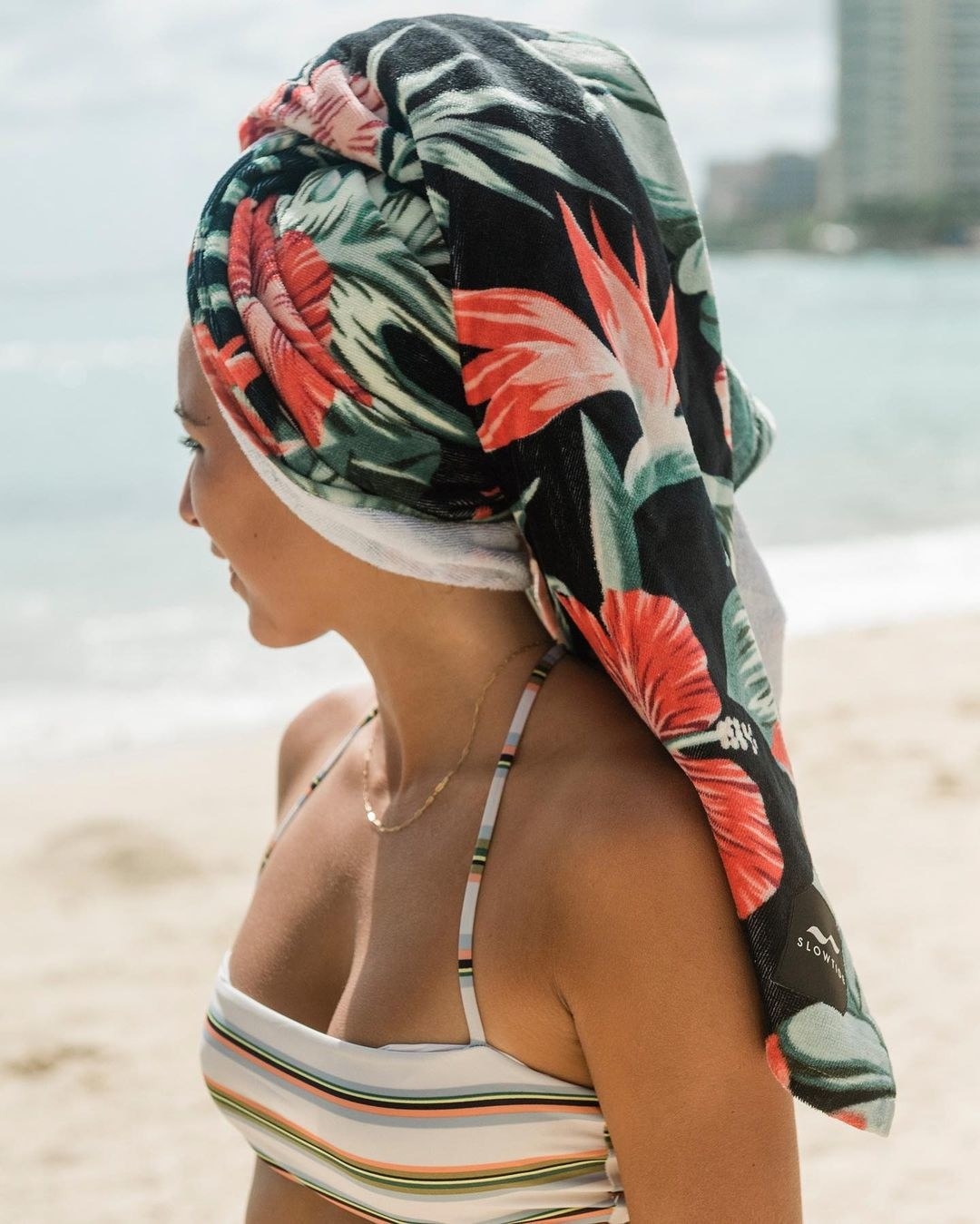 A person wearing the floral-printed beach towel on their head