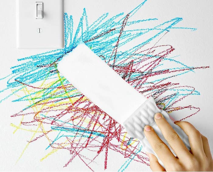 hand using a magic eraser to clean crayon from a wall