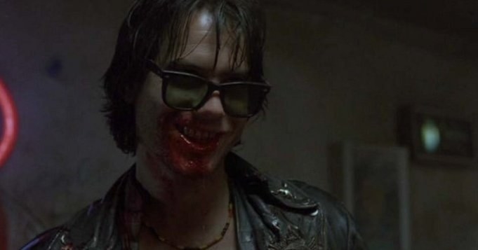 Man in sunglasses smiles while mouth is covered in blood