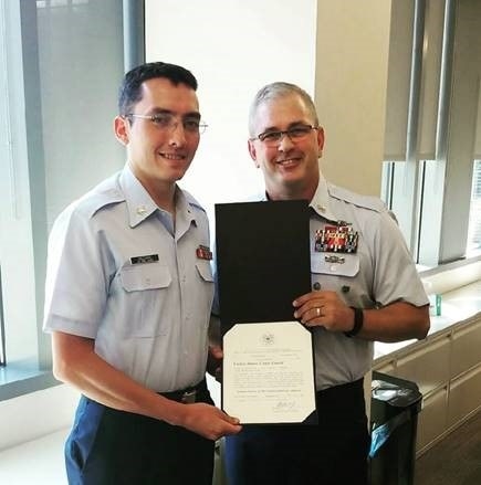 YN1 Christian Hazzard poses with a senior officer after receiving an award
