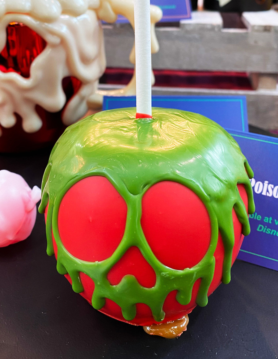 A perfectly red candy apple coated with green sugar frosting dripping to look like poison forming the face of a skull