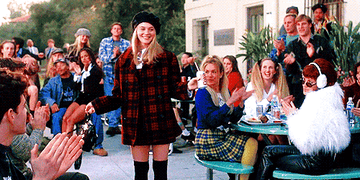 A gif from clueless of Cher curtsying as her whole class claps for her