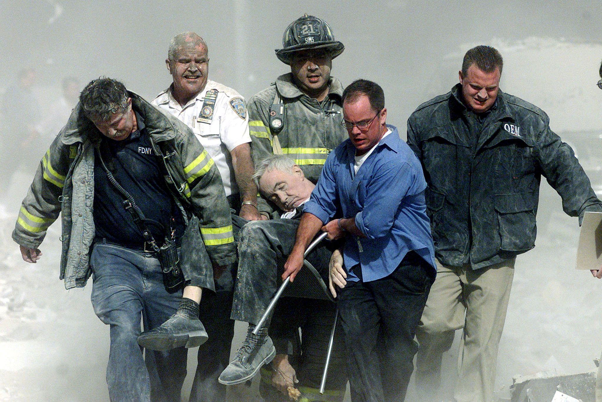 An unconscious man is carried out on a chair by firefighters 