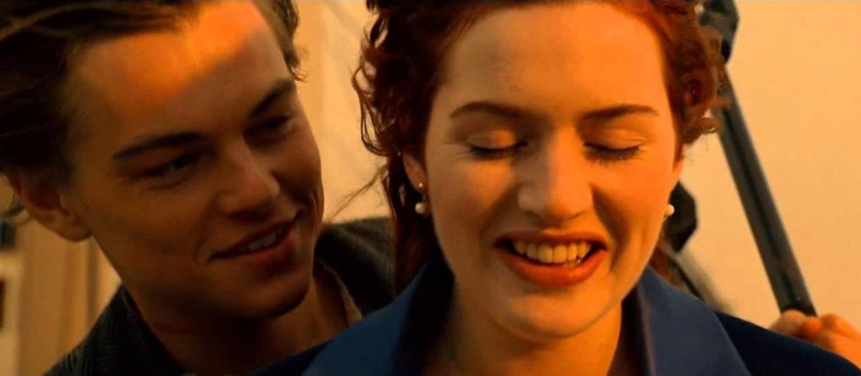 DiCaprio and Winslet stand at the front of the boat, smiling