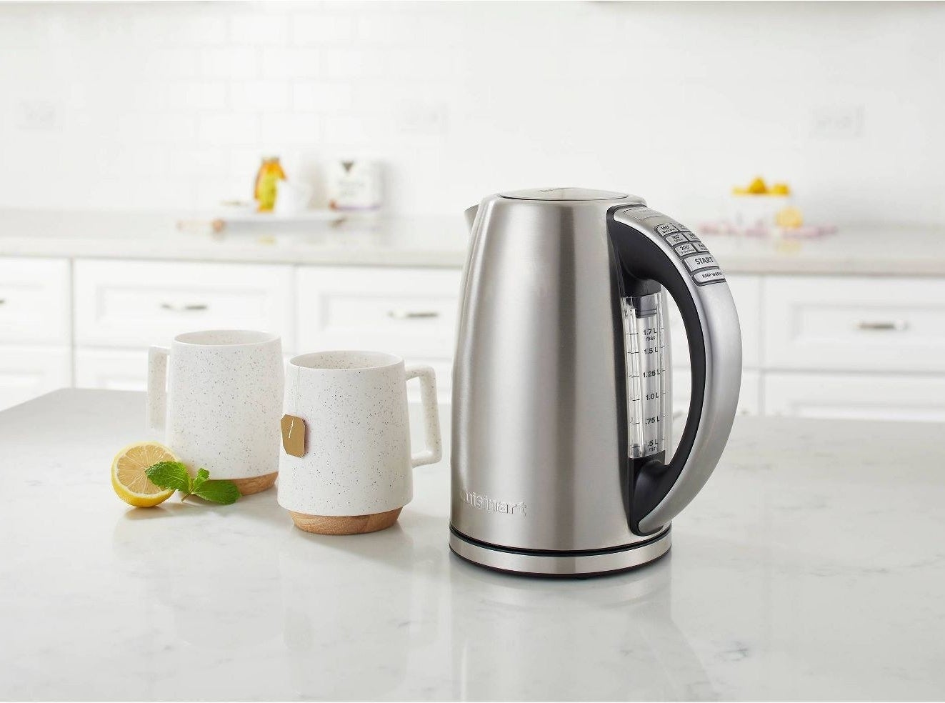 stainless steel electric kettle on counter next to mugs