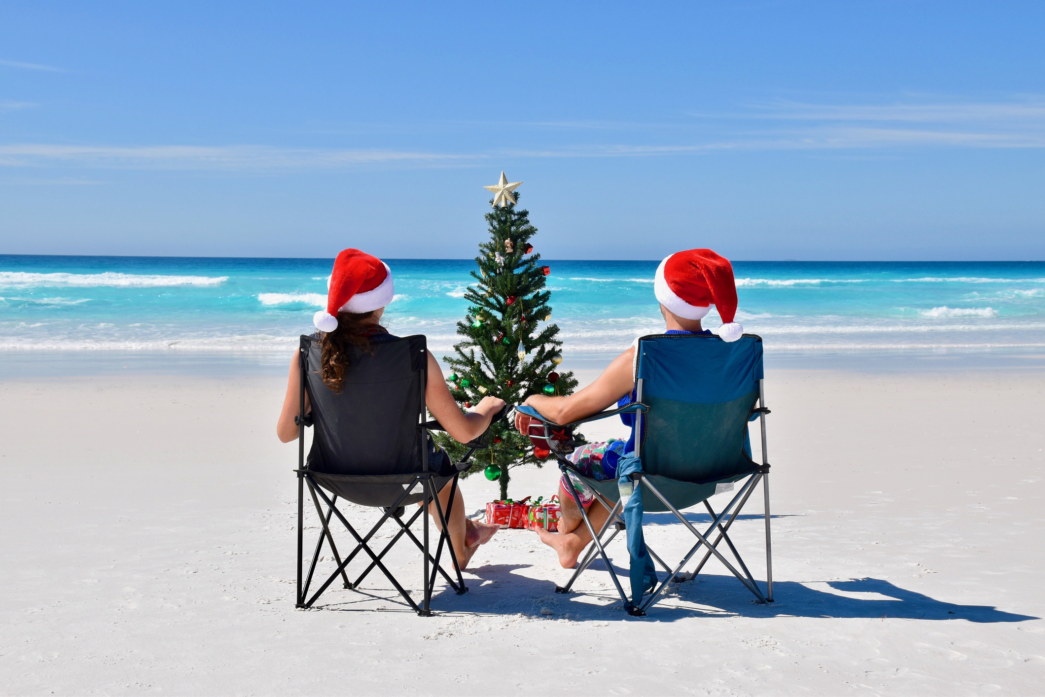 Two Australians on the beach in Christmas hats