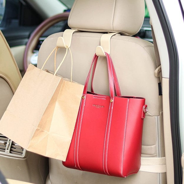 beige car seat headrest hook holding up a brown bag and red tote bag