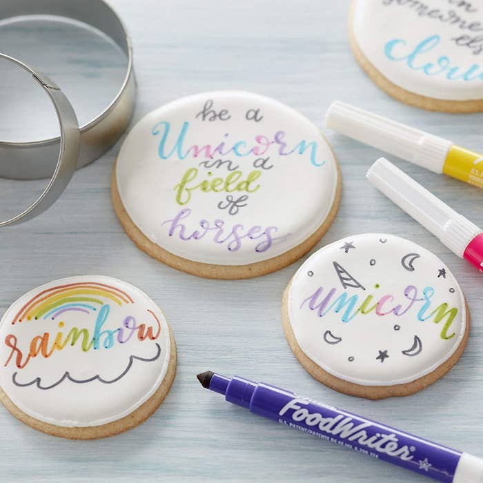 A bunch of markers next to a bunch of iced cookies