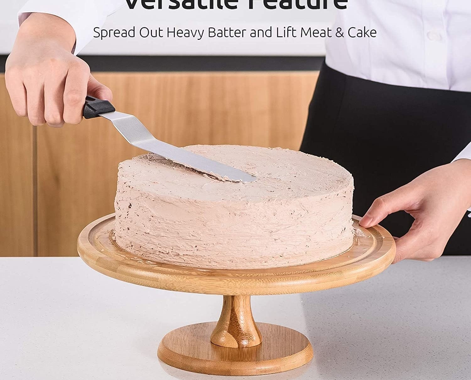 A person icing a cake with a metal spatula