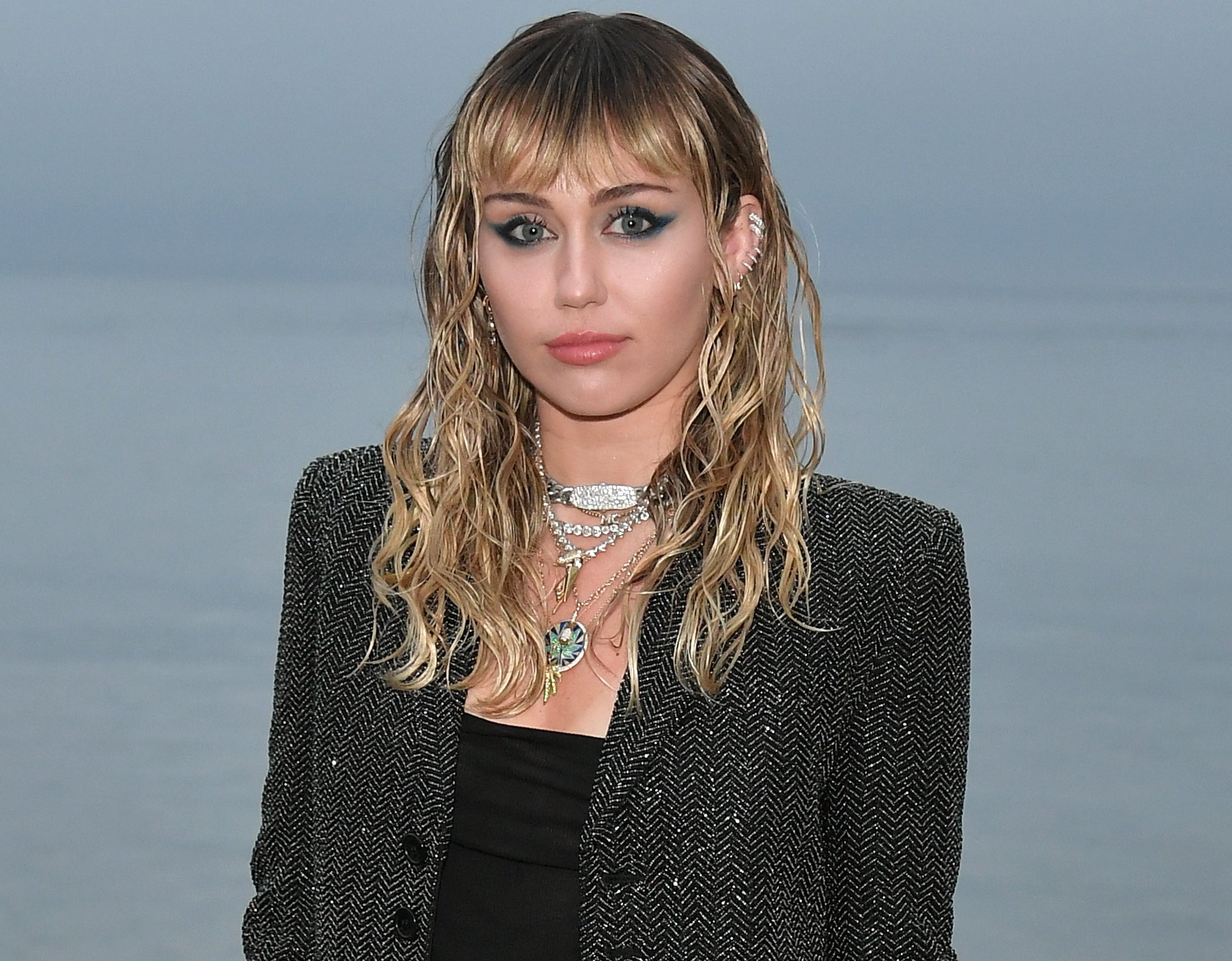 Miley wears a black blazer jacket and tank top with silver necklaces