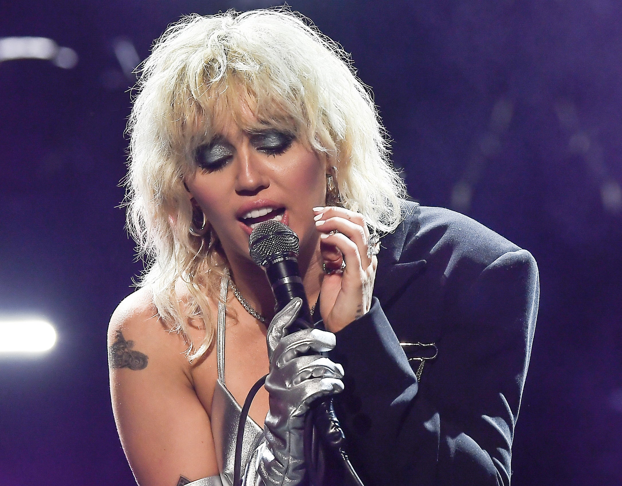 Miley performs at the festival wearing a silver bikini top and a cropped blazer