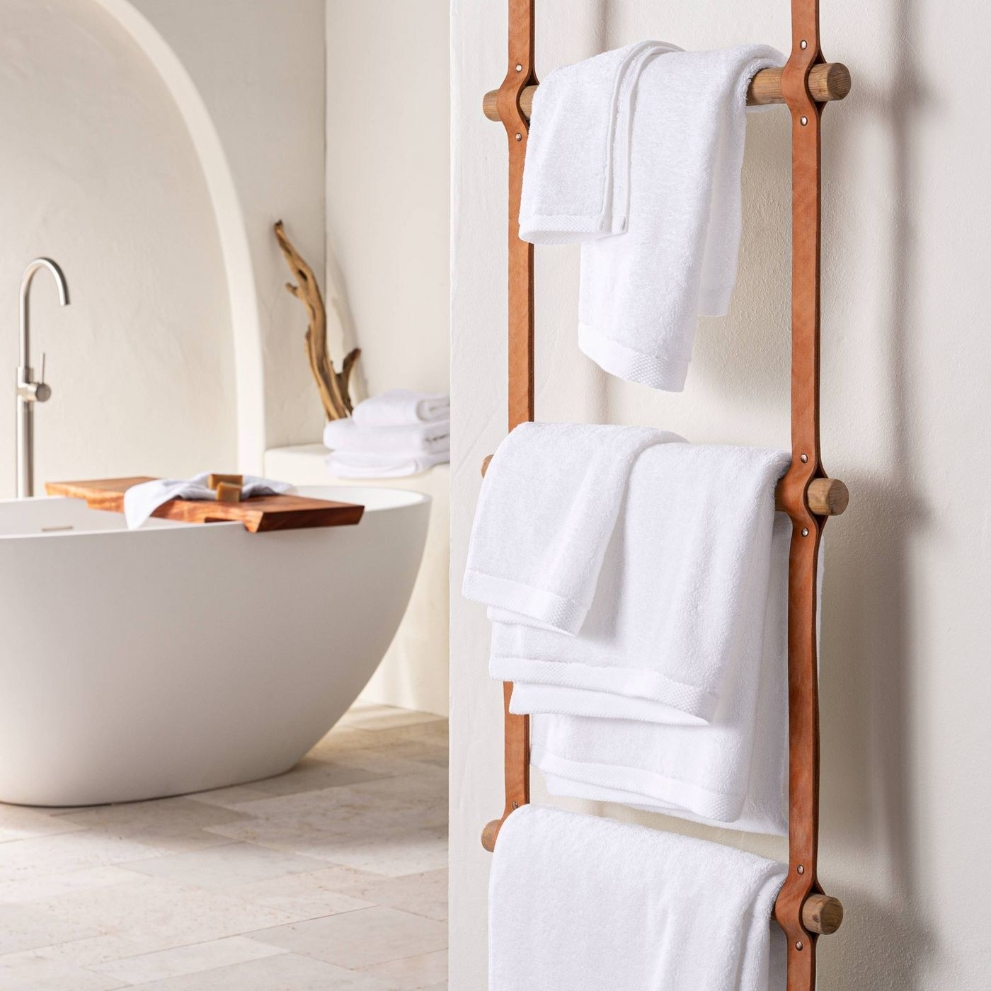 white towels of different sizes hung next to a bathtub