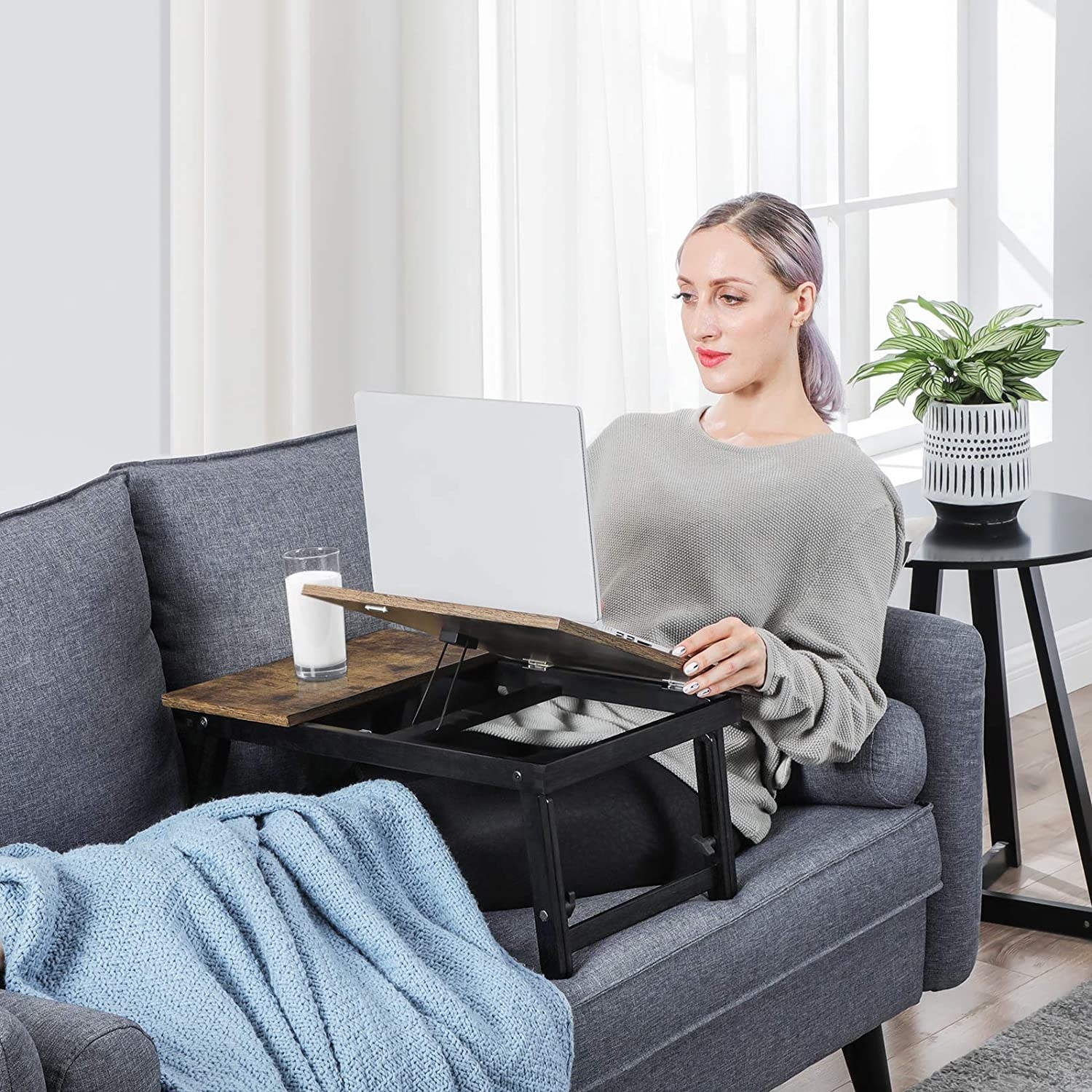 A person using the table while lying on a couch