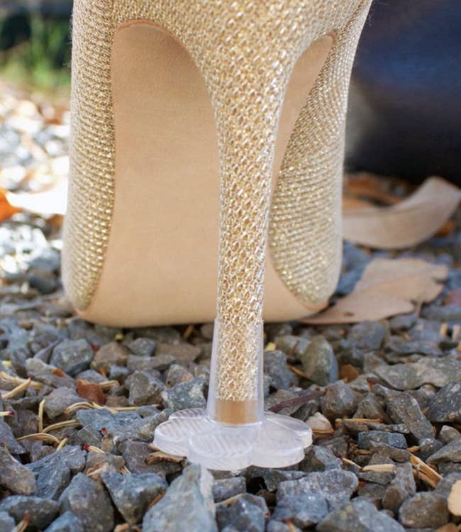 plastic flower-shaped cap on stiletto heel keeping it from sinking into gravel