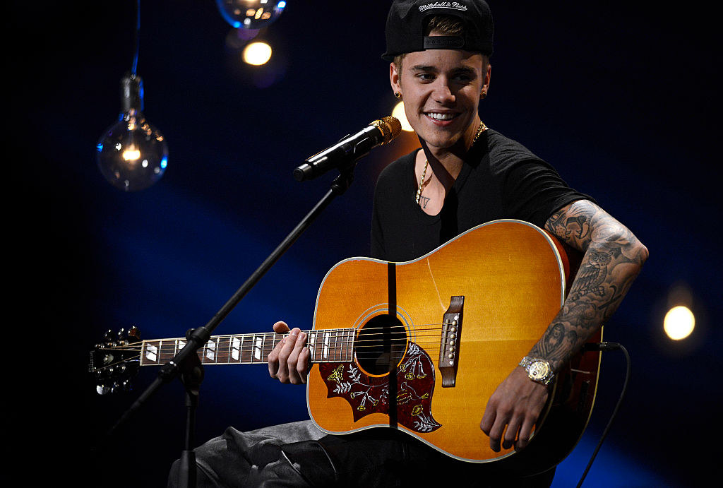 Justin Bieber performing with an acoustic guitar on stage