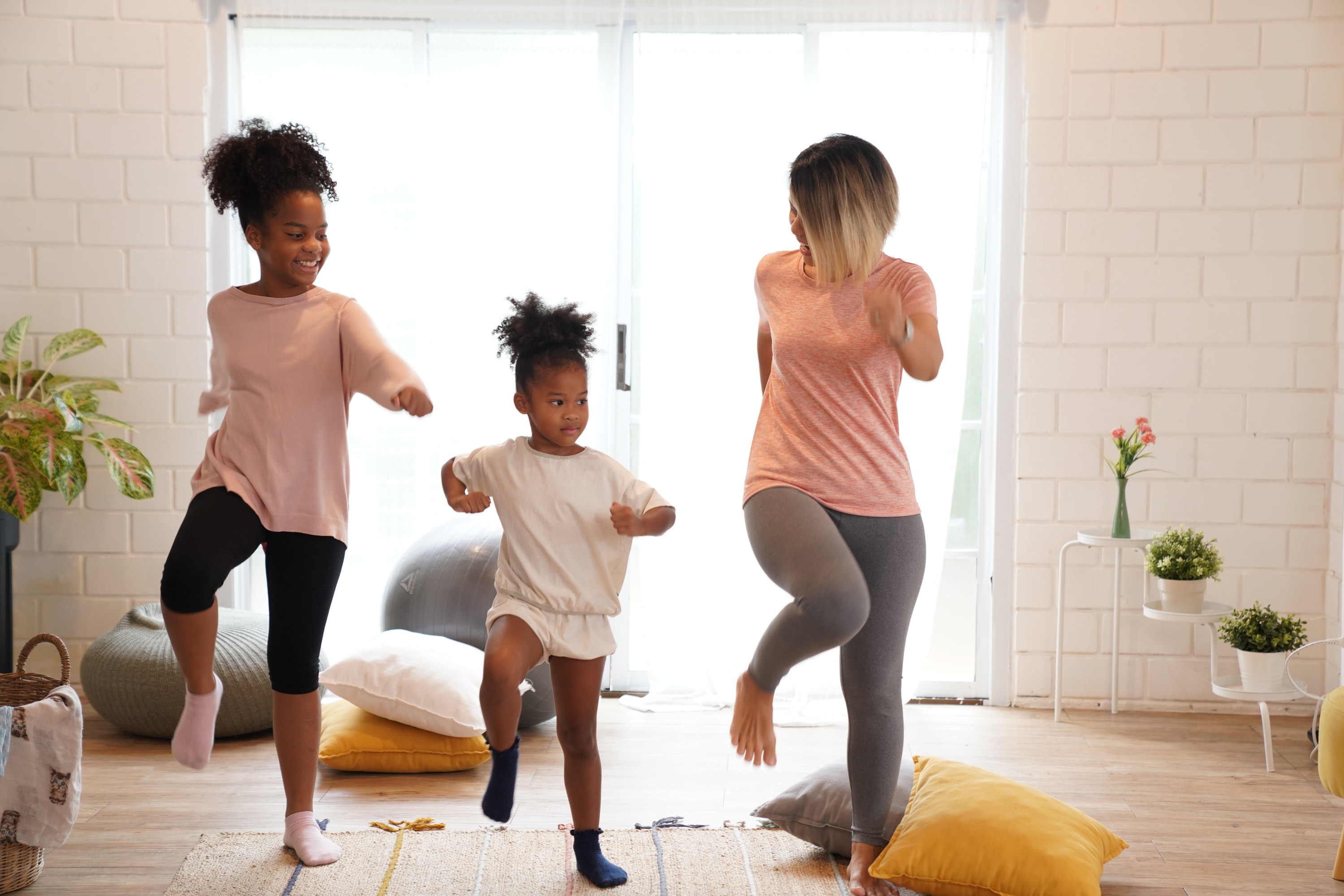 Two kids and their mom dance in their living room.