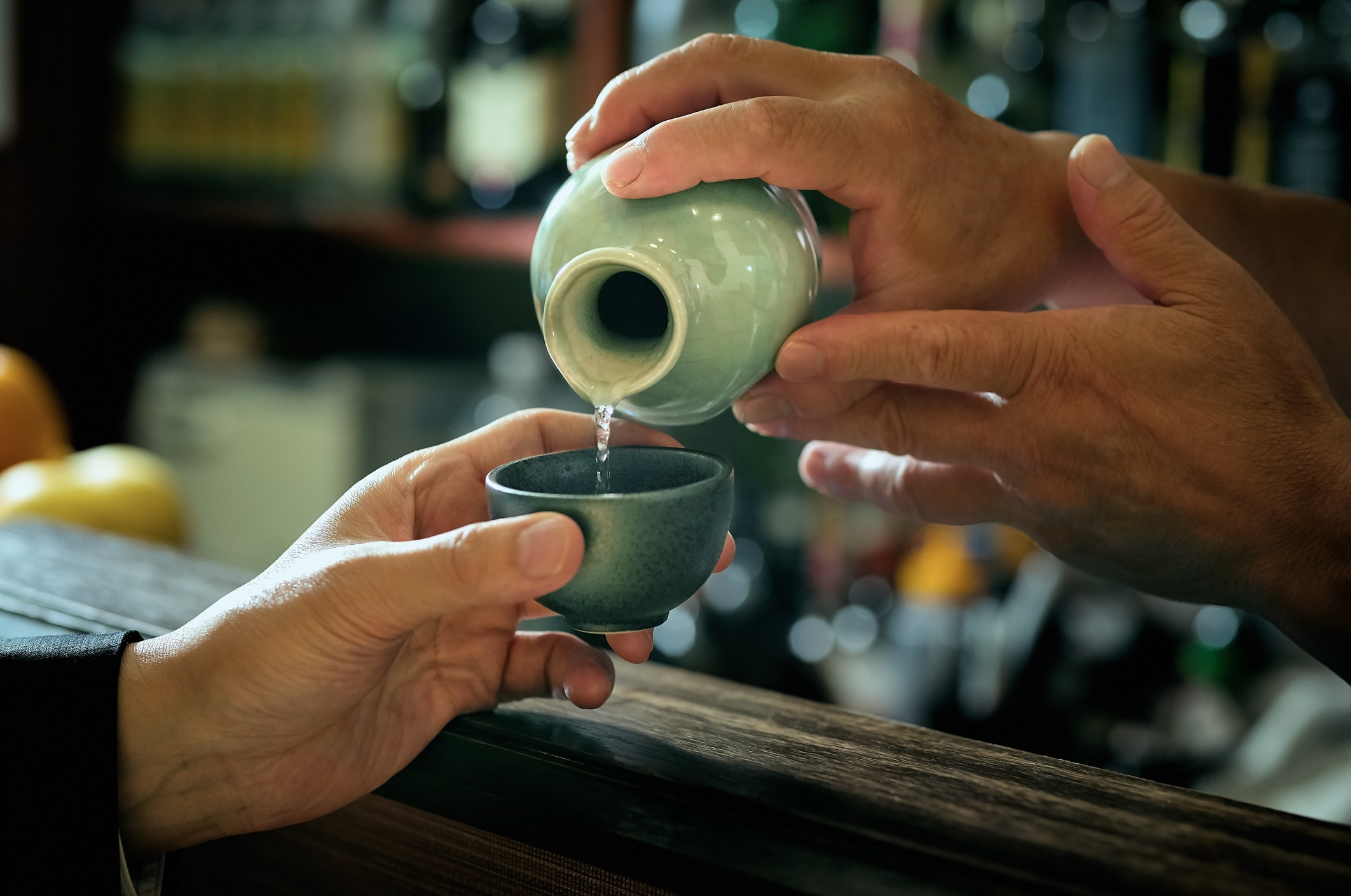 A man pouring sake into a class.