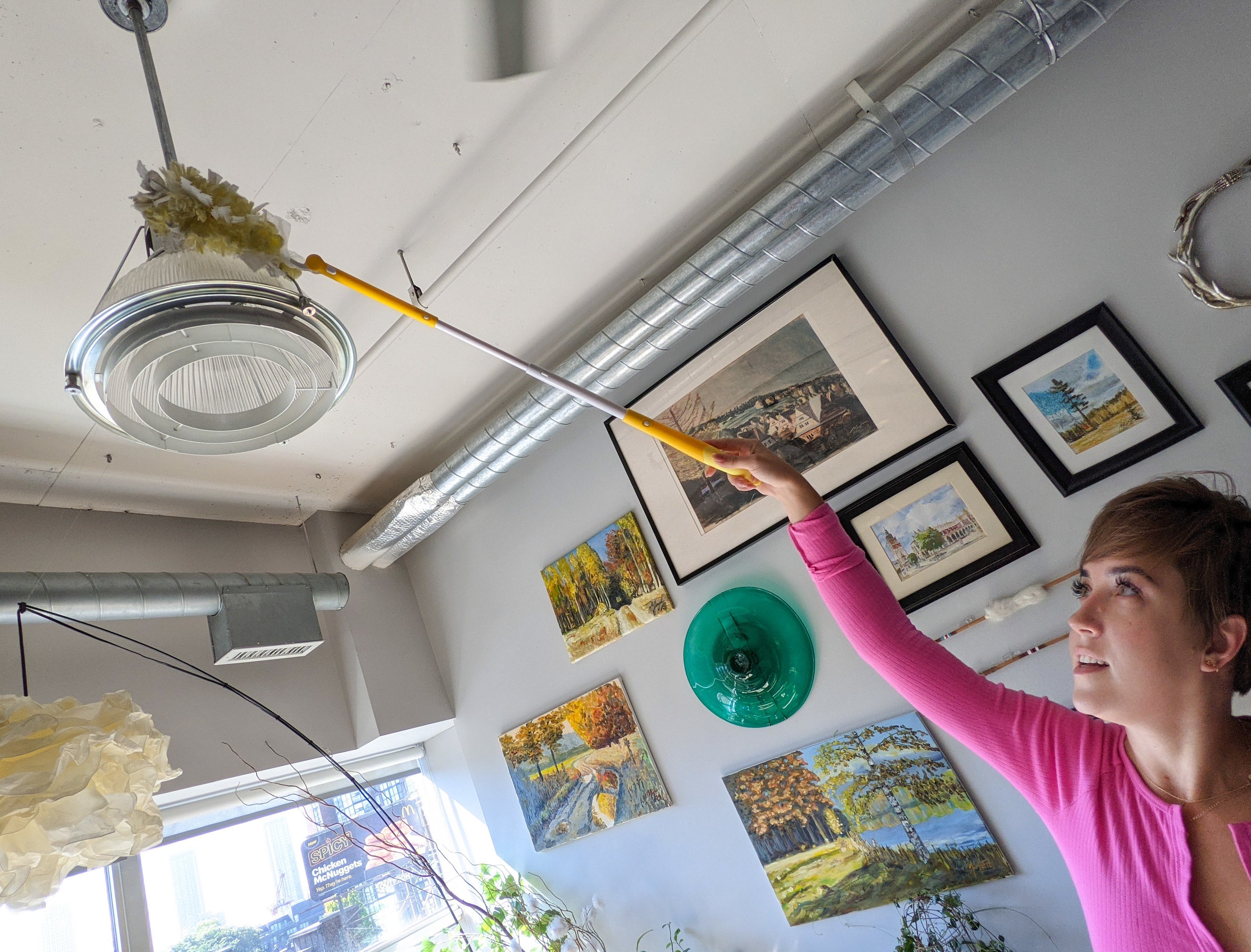 Victoria using the extendable swiffer to clean a light fixture