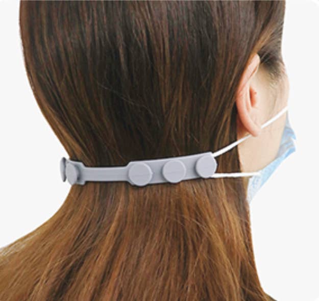 A model wearing a mask that is pulled together around the back of their head by the silicone ear saver, which has three different toggles on the back for sizing