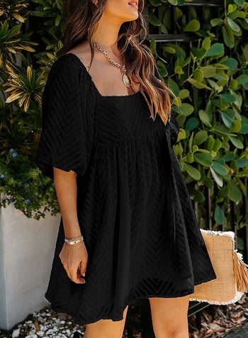 A model wearing the three quarter length sleeve dress in black