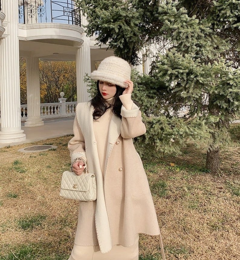 Model is wearing a cream coat with a cream dress and boots