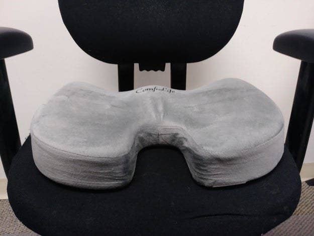 A reviewer's swivel office chair with a gray memory foam cushion resting on it