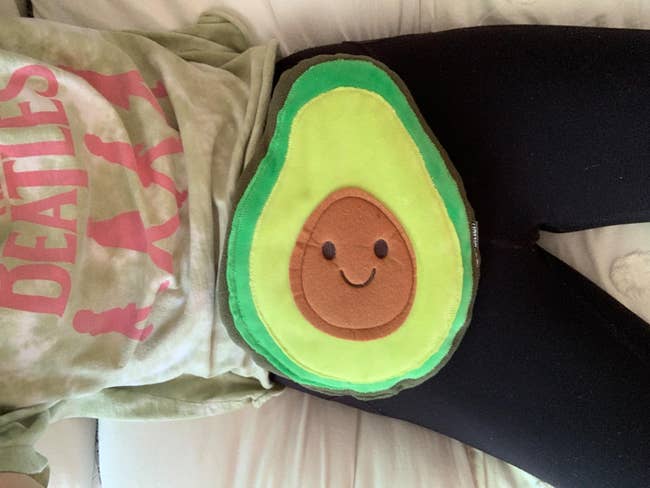 reviewer with avocado-shaped heating pad on stomach