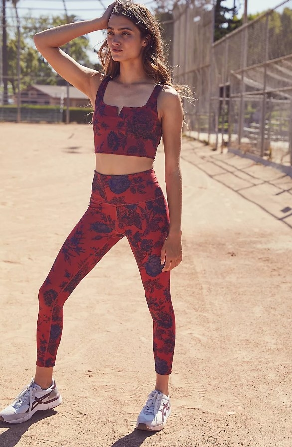 Model wearing red leggings with blue floral design and matching top