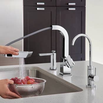 The soap dispenser in a kitchen next to a matching faucet
