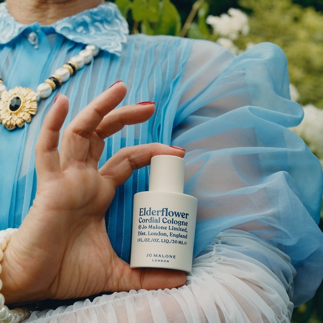 Someone holding the ceramic bottle of the perfume against a colourful tulle outfit