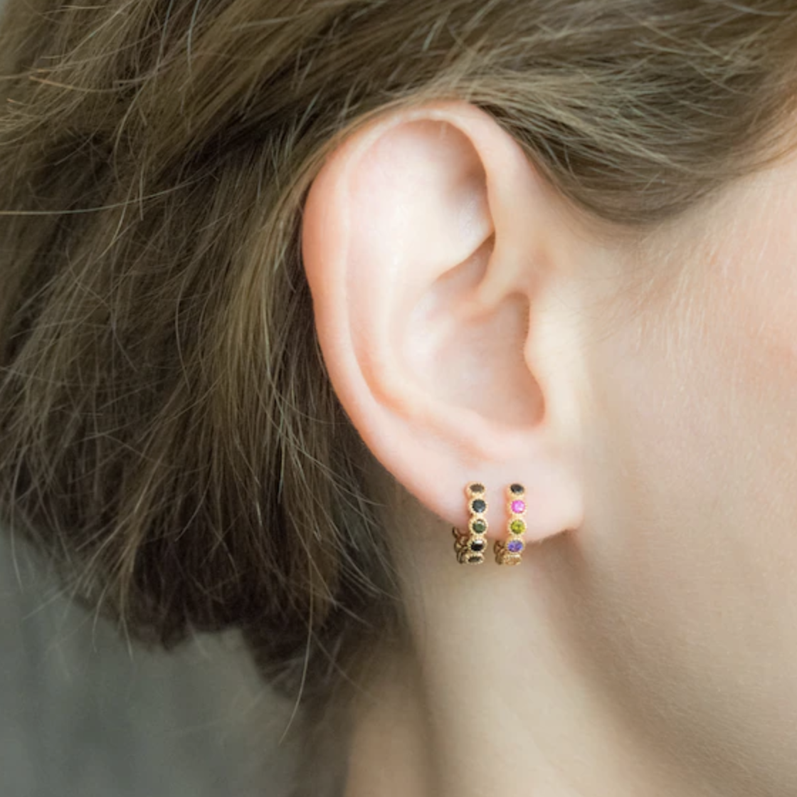 model wears small huggie hops with multi-colored stones
