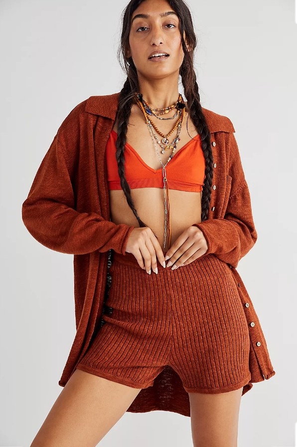 Model wearing burnt orange button-down sweater with matching shorts and orange bralette