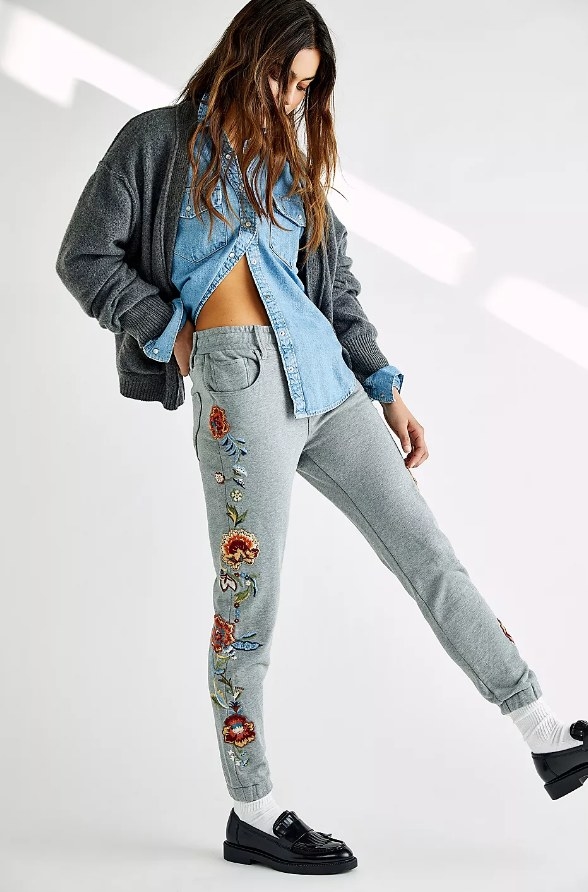 Model wearing gray joggers with embroidered flower design down the leg
