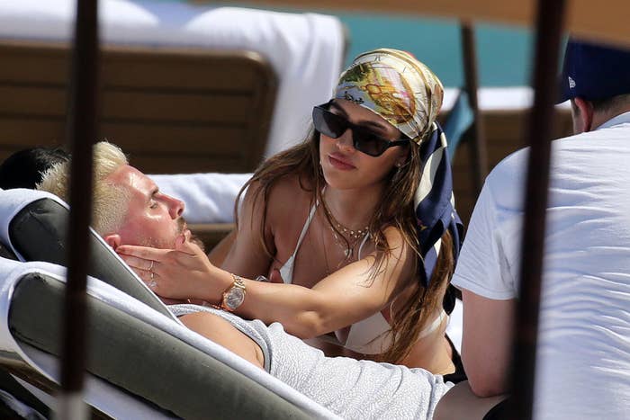 Scott lounging on a beach chair as Amelia leans over him